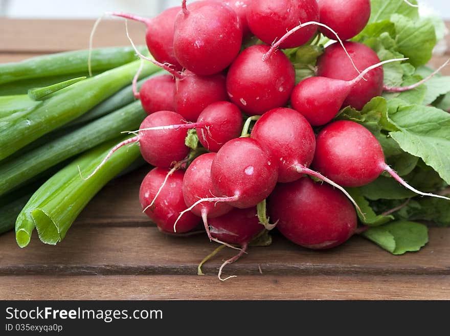 Red radishes and green onions on a wooden table. Red radishes and green onions on a wooden table