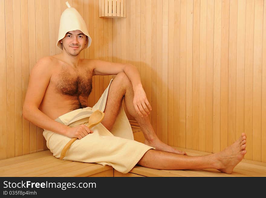 Young handsome man in a towel relaxing in a russian wooden sauna. Young handsome man in a towel relaxing in a russian wooden sauna