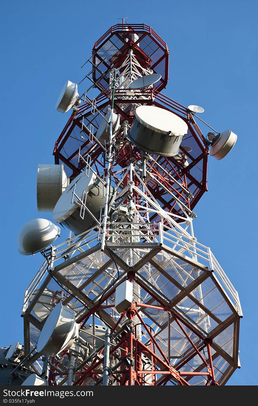 Huge communication antenna tower and satellite dishes against blue sky. Huge communication antenna tower and satellite dishes against blue sky