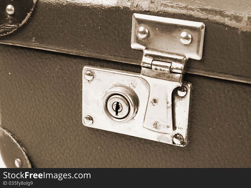 Vintage suitcase with a lock in sepia in close up