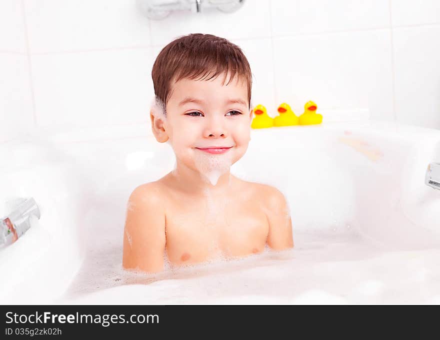 Cute four year old boy taking a relaxing bath with foam. Cute four year old boy taking a relaxing bath with foam