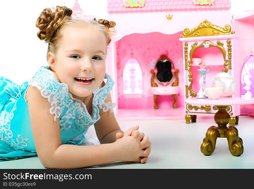 Beautiful little girl in princess dress playing with her toy castle.