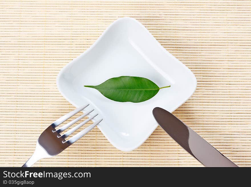 Green leaf on a plate as vegetarian diet - concept of healthy dieting