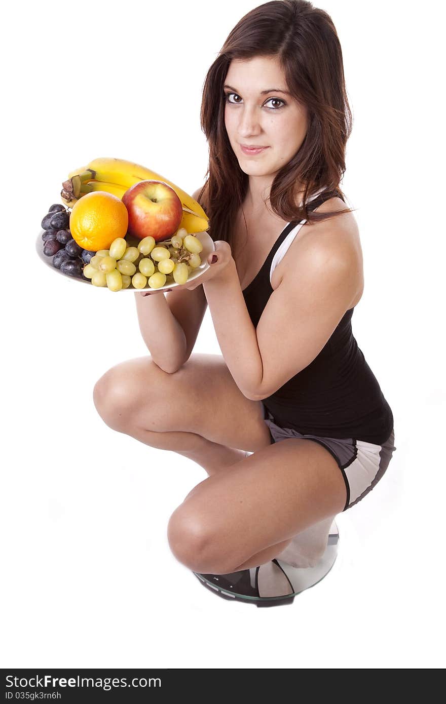 A woman is holding up a plate of fruit while smiling. She is satisfied with her weight because of her healthy diet. A woman is holding up a plate of fruit while smiling. She is satisfied with her weight because of her healthy diet.