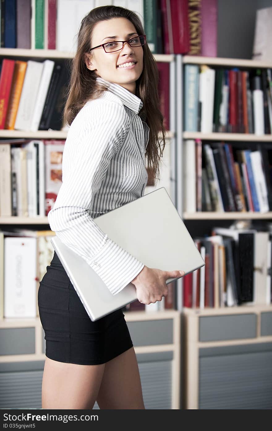 Young women stands near bookshelf