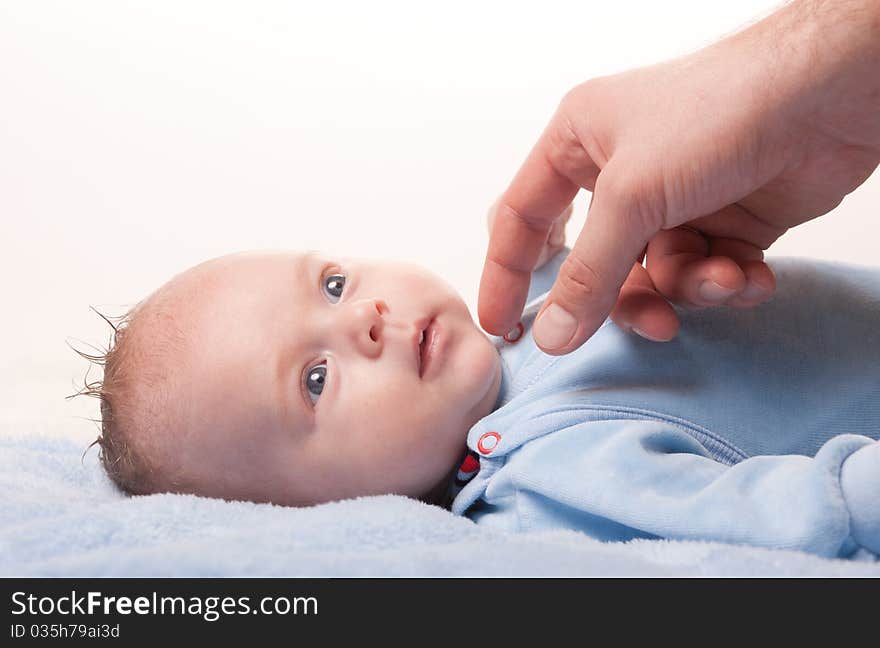 Newborn baby with fathers hand on blue towel