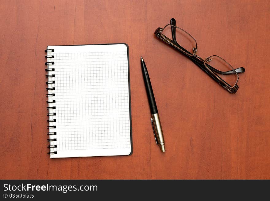 Glasses, notepad with pen lying on the table