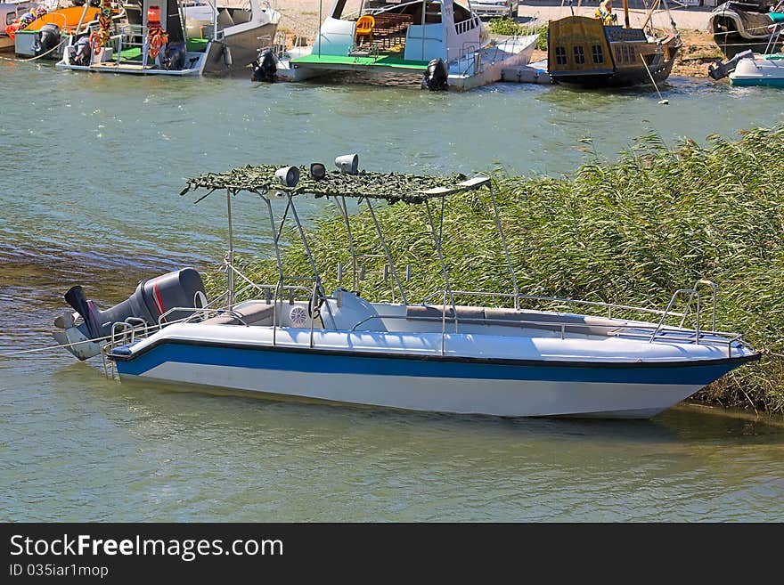 Motorboat with elevated motor on water near boat station.