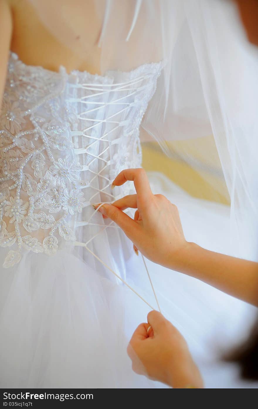 Hands helping with bride's white corset. Hands helping with bride's white corset