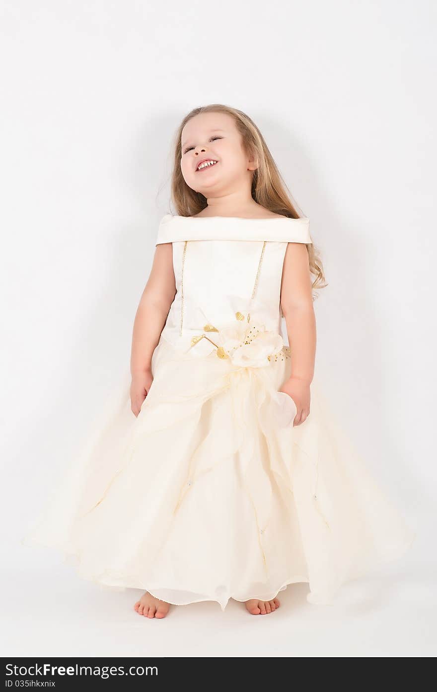 A beautiful little girl in a white dress in the studio