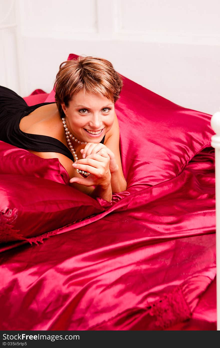 Charming young woman in a black dress on a bed