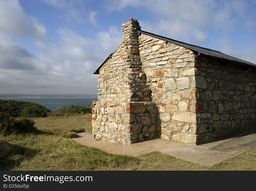 Stone building overlooking sea with blue sky and clouds