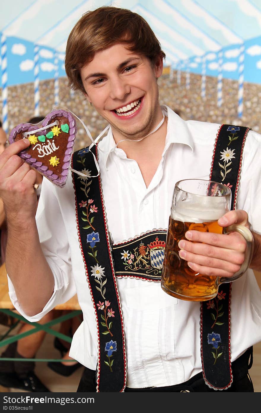 Handsome bavarian man holding a beer and a gingerbread heart. Handsome bavarian man holding a beer and a gingerbread heart