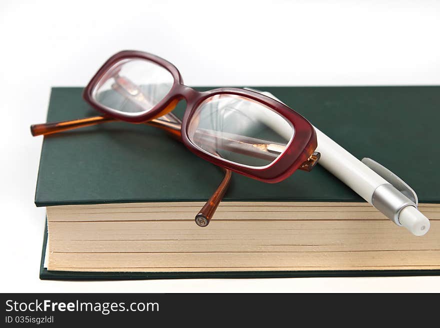 Glasses on book and pen isolated in white