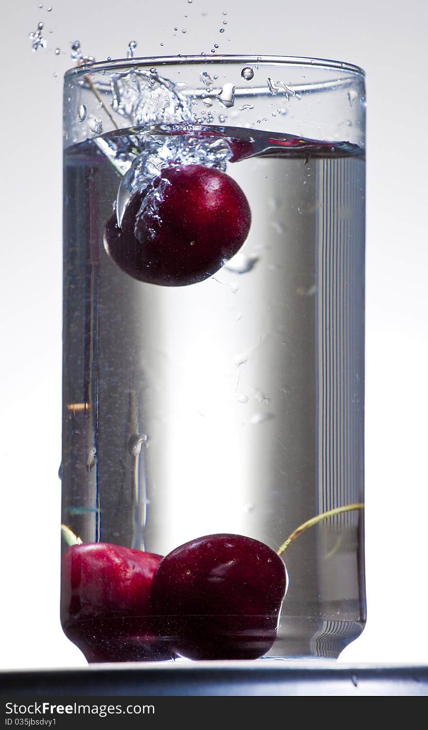 Image of Cherries splashing into a glass of water. Image of Cherries splashing into a glass of water