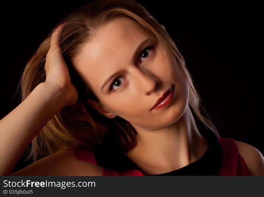 Beautiful young woman playing with her hair looking straight in camera on black background