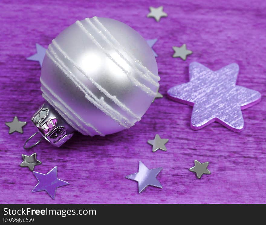 Bright glass bauble ornament and stars. Purple colors background. Bright glass bauble ornament and stars. Purple colors background