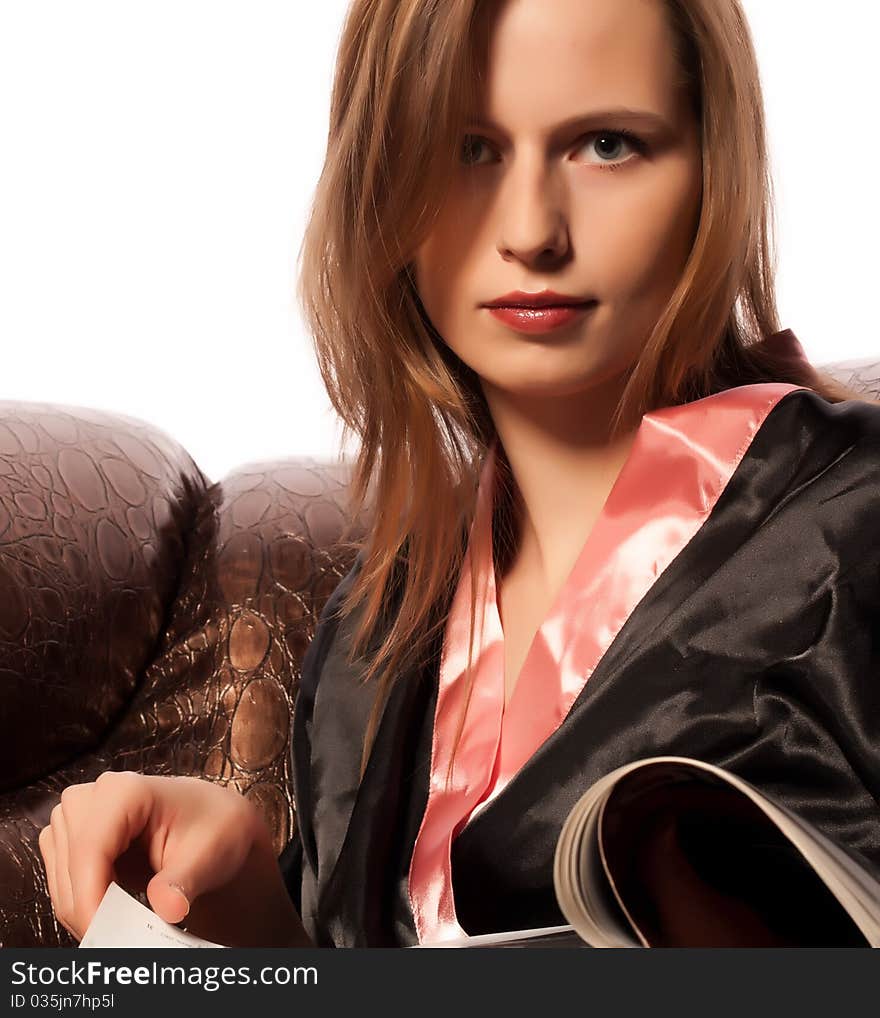 Young woman sitting on sofa reading magazine