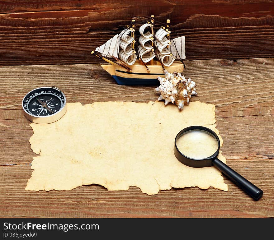 Model classic boat, compass and rope on wood background