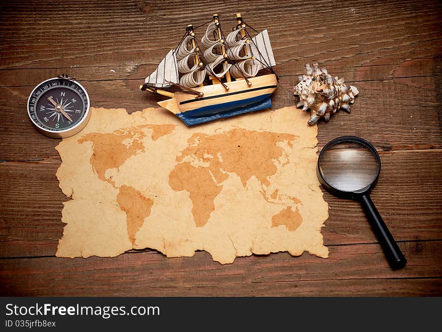 Model classic boat, compass and loupe on wood background