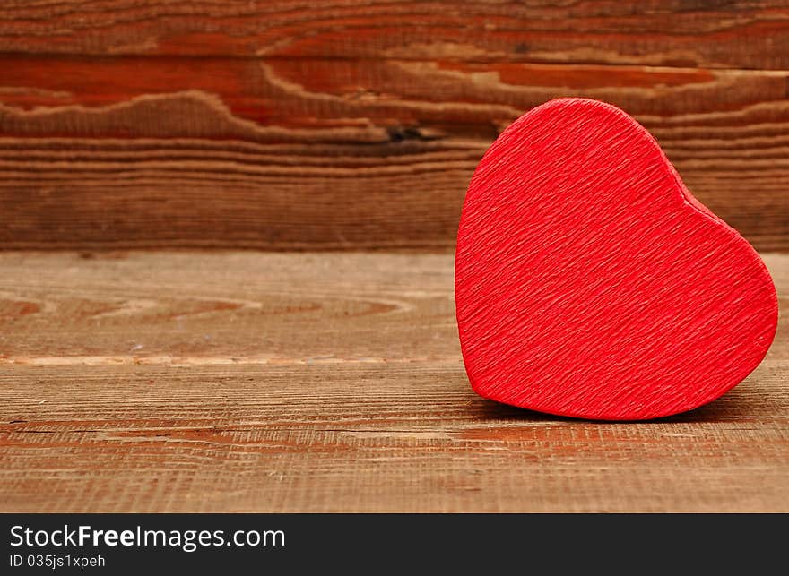 Red box in heart shape on wood background