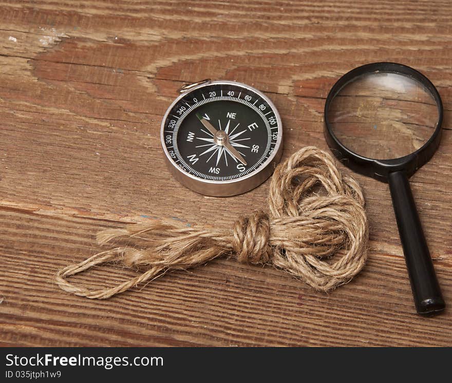 Rope, compass and magnifying glass on wood background