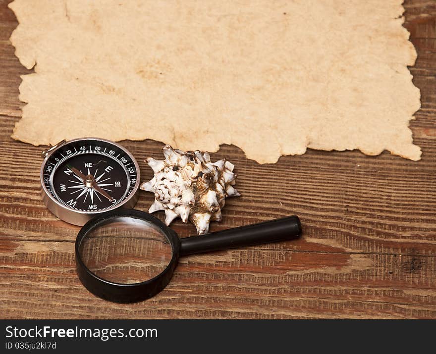 Old paper, compass and magnifying glass on wood background