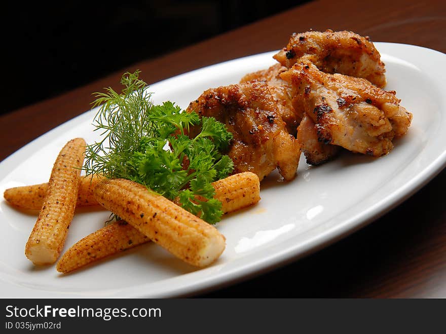 Grilled chicken meat with gravy and corn on a plate