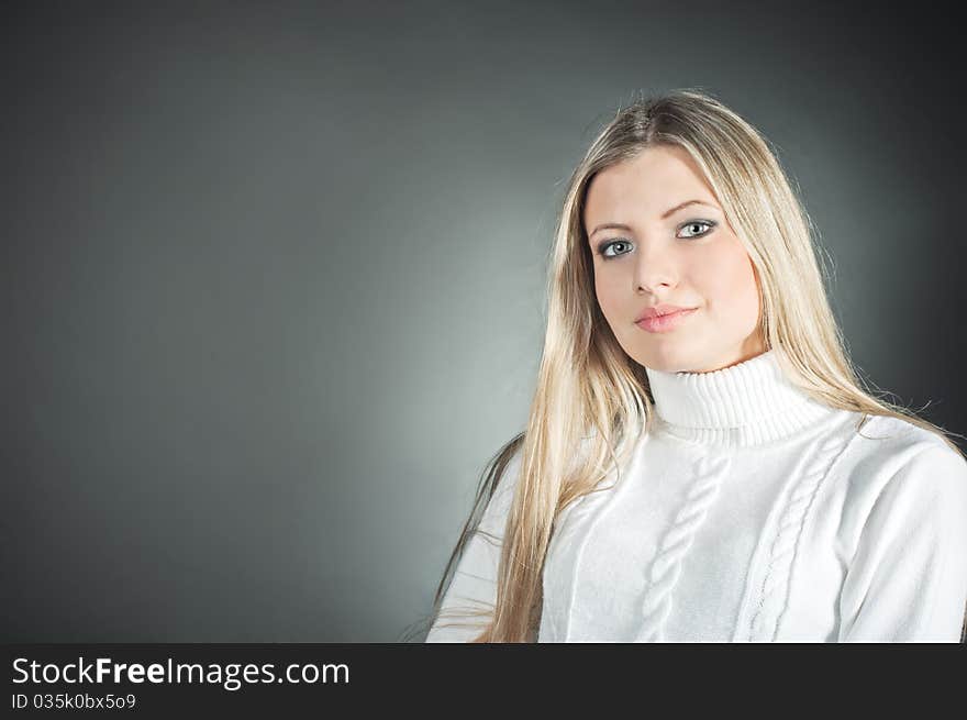 Beautiful blond girl wearing in the white sweater on the black background