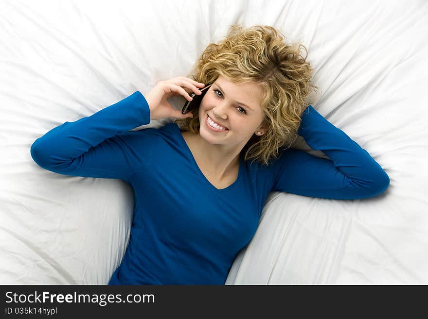 Beautiful teenage girl lying down talking on a cell phone