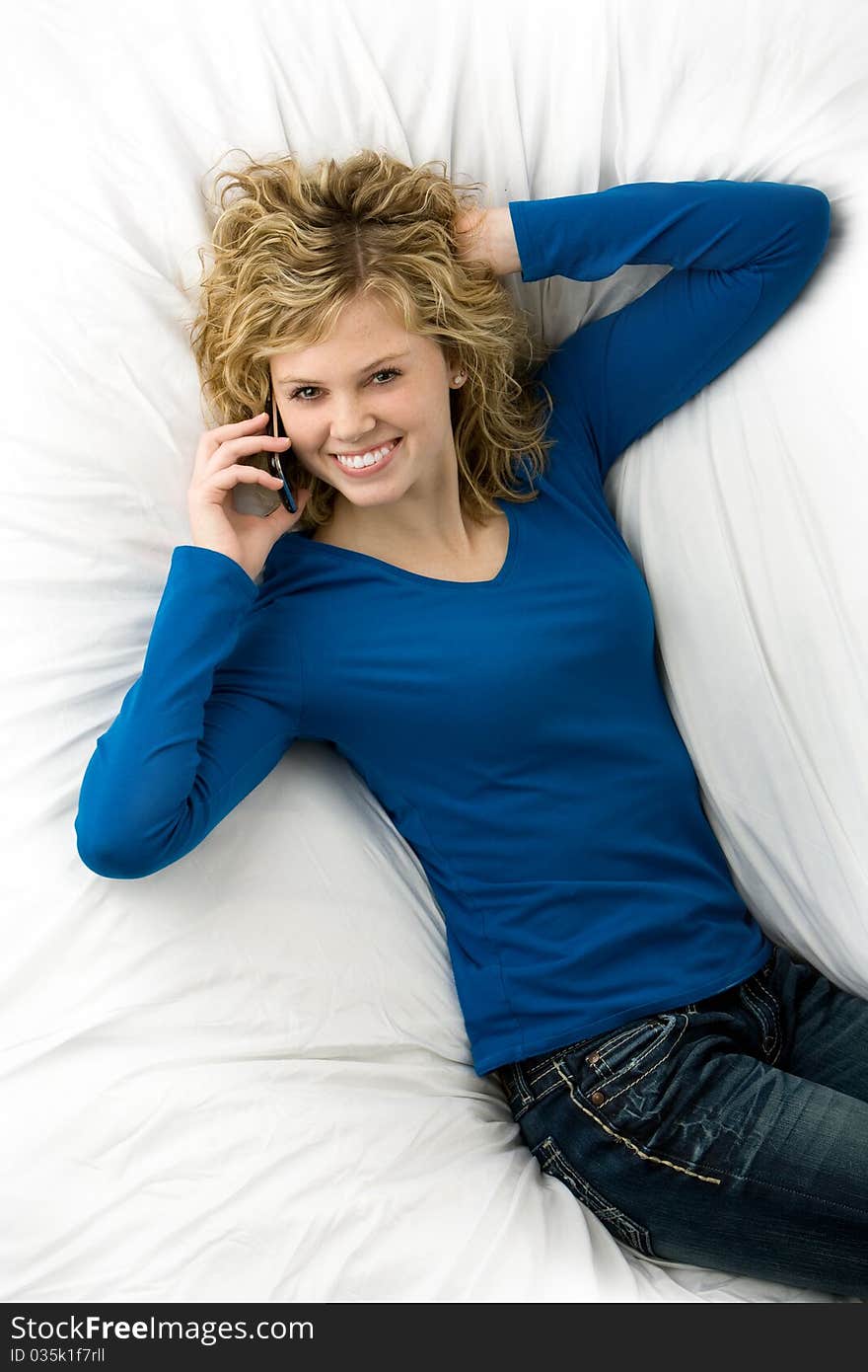 Beautiful teenage girl lying down talking on cell