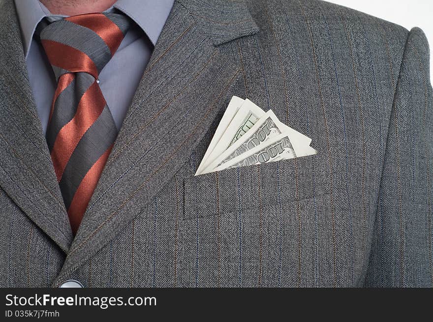 A businessman wearing a suit and tie with cash sticking out of his pocket.