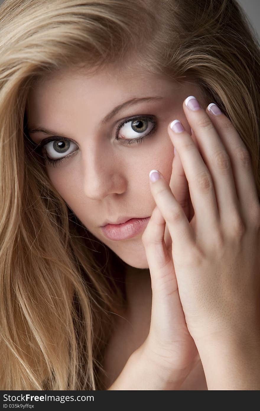 Intense close-up of pretty teenage girl with big eyes, beautiful hair and manicured nails in a red dress. Intense close-up of pretty teenage girl with big eyes, beautiful hair and manicured nails in a red dress