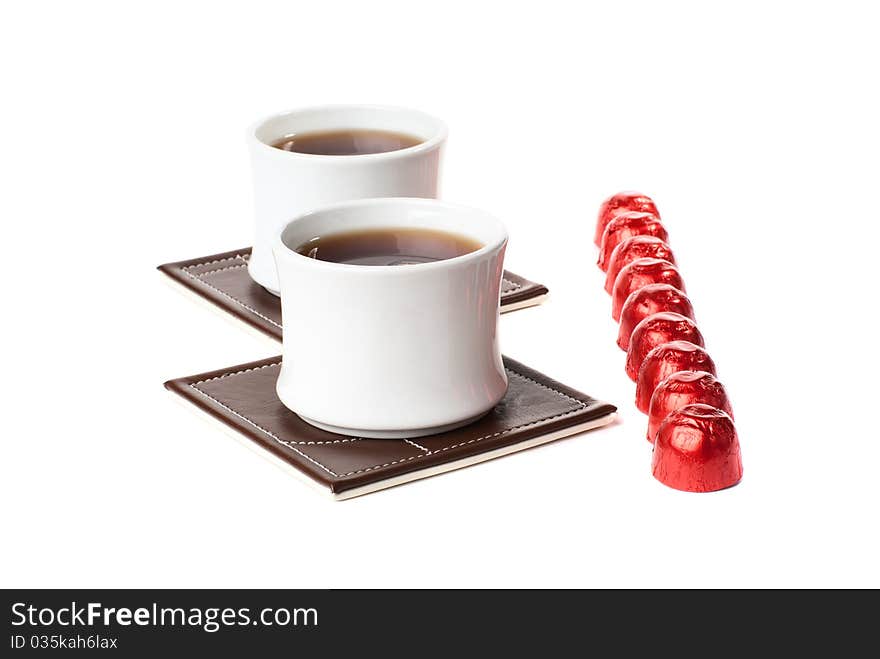 Two cups of tea on the table mat with sweets. Isolated on white background. Two cups of tea on the table mat with sweets. Isolated on white background.