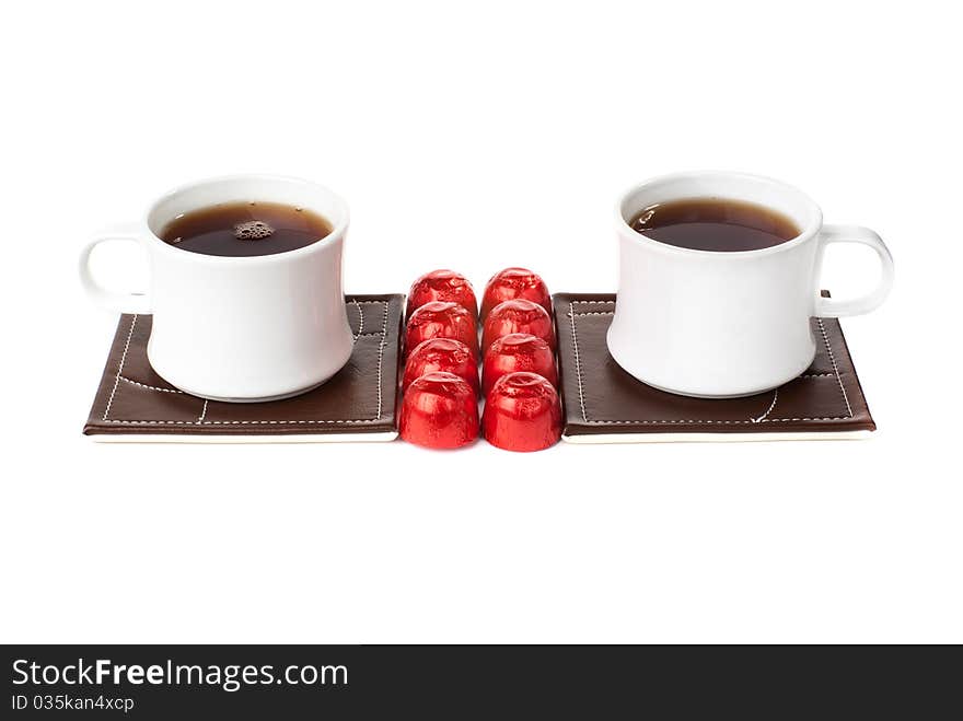 Two tea cups ot table mats with sweets. Isolated on White background. Two tea cups ot table mats with sweets. Isolated on White background.