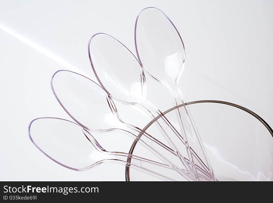 Transparent plastic spoons on a luminous background