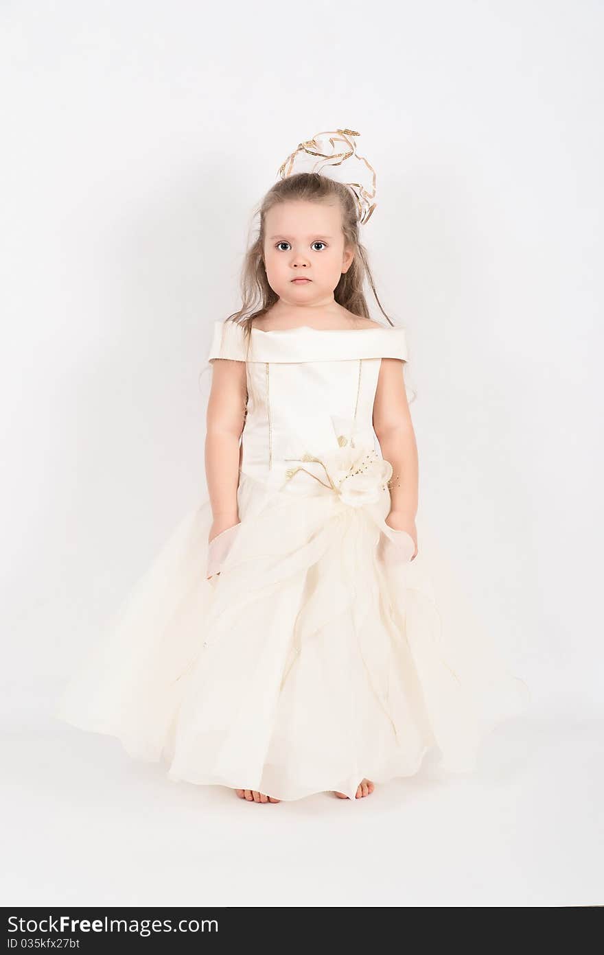 A beautiful little girl in a white dress in the studio