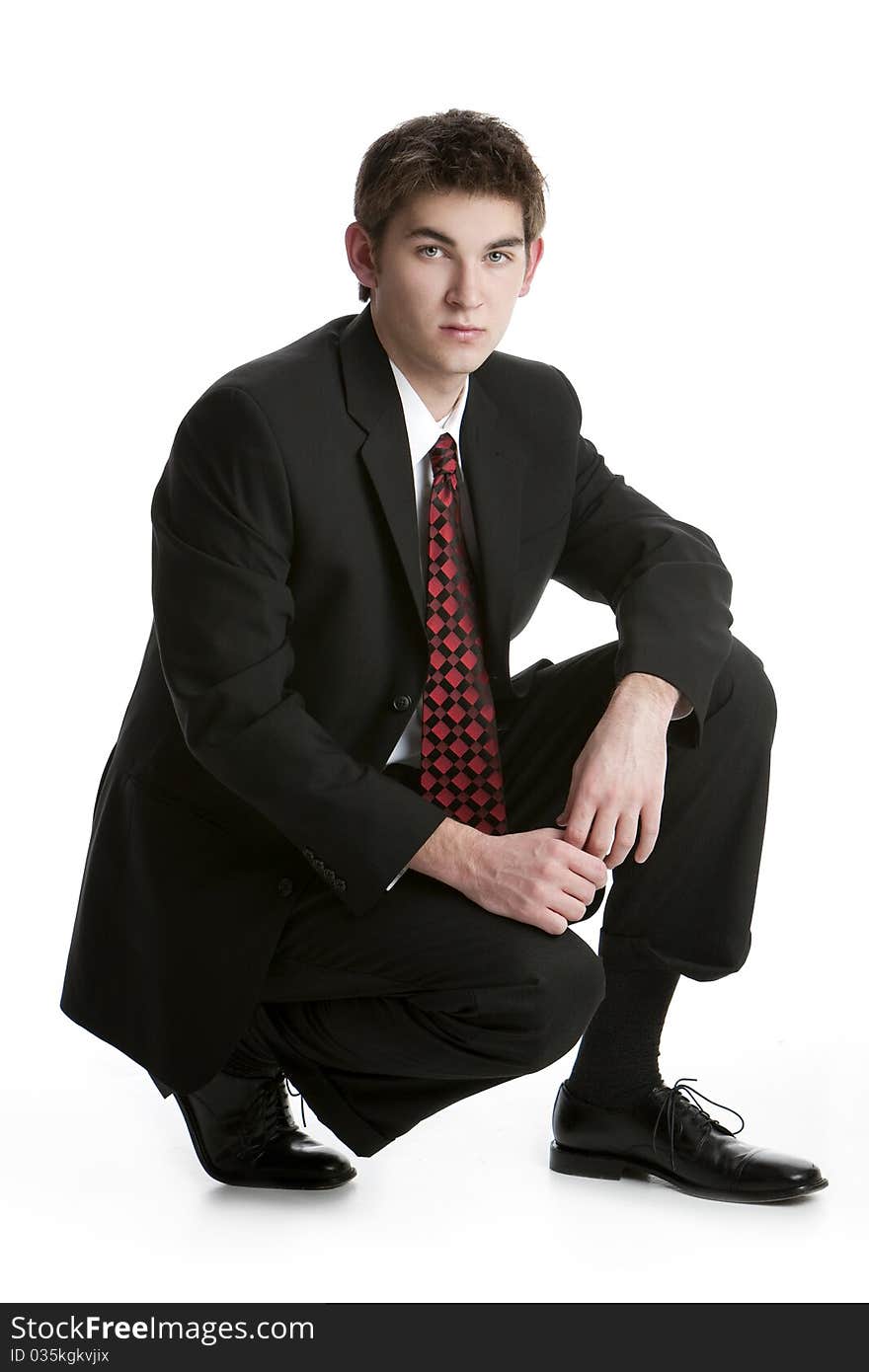 Attractive teenage boy kneeling in a suit