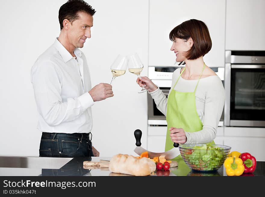 Happy Couple Toasting With Glass Of Wine while preparing dinner