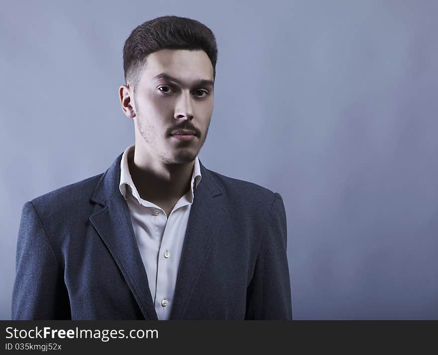 Young attractive man in suit on gray background