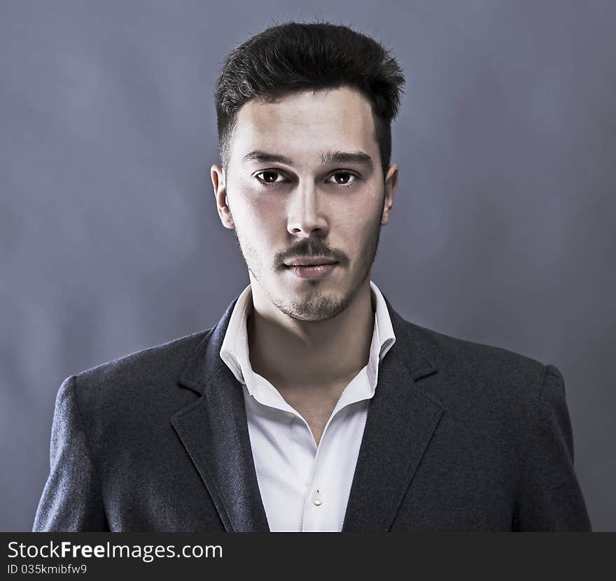 Young attractive man in suit on gray background