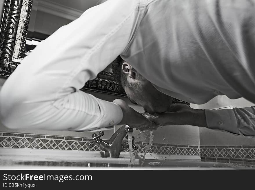 Man washing face in bathroom sink