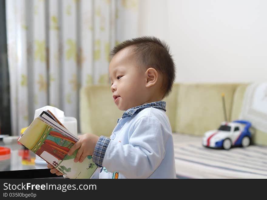 A chinese boy is reading a cartoon book in home. A chinese boy is reading a cartoon book in home.