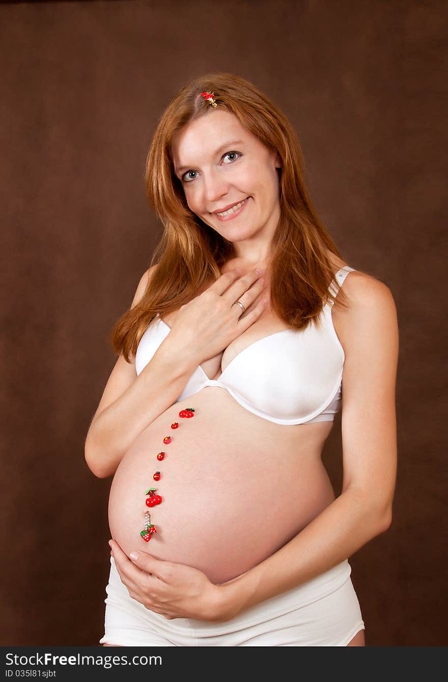 Pregnant young woman in white underclothes with funny motif on abdomen