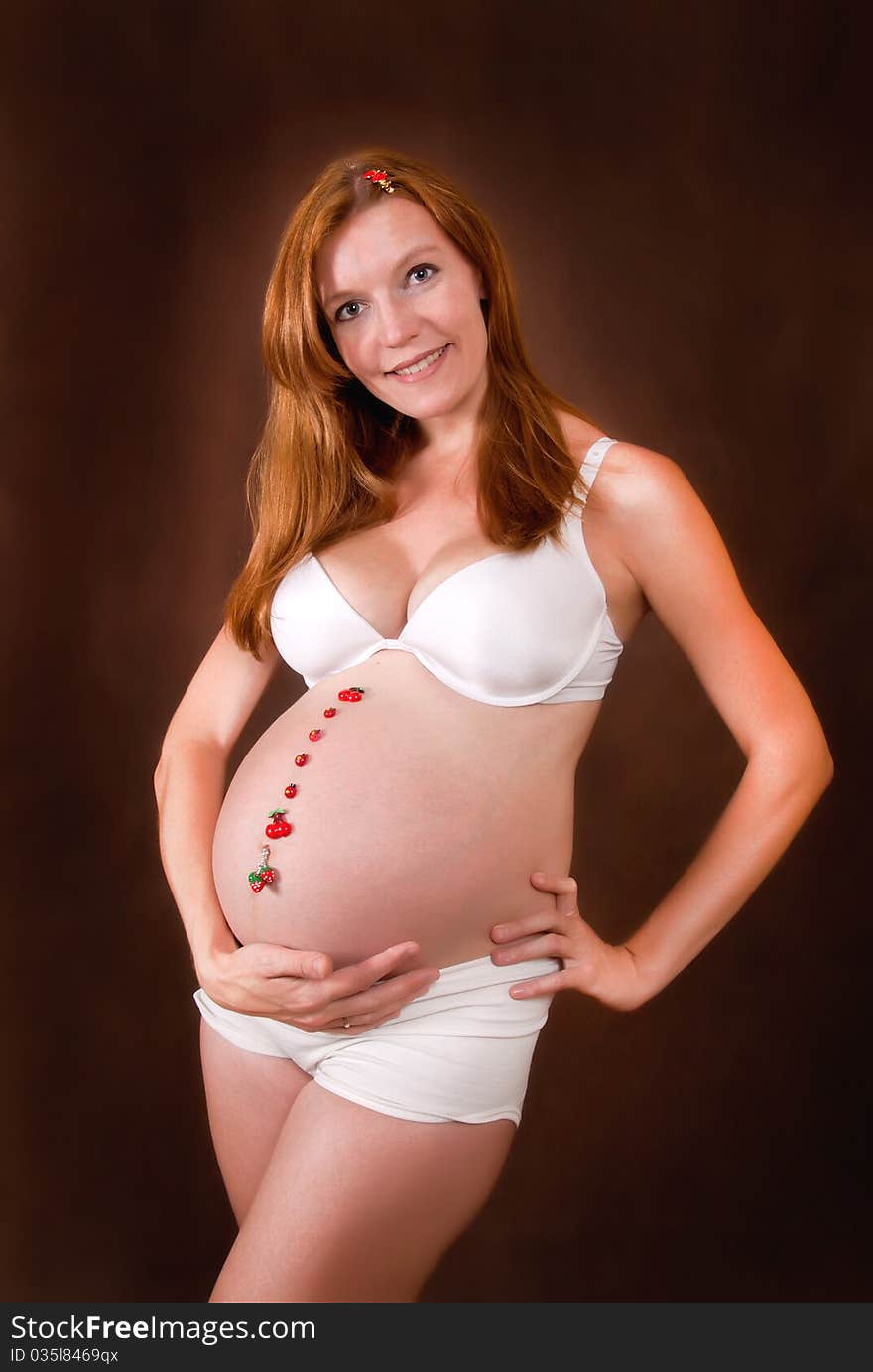 Pregnant young woman in white underclothes with funny motif on abdomen