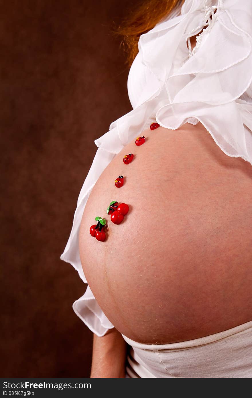 Pregnant young woman in white blose with funny motif on abdomen. Pregnant young woman in white blose with funny motif on abdomen