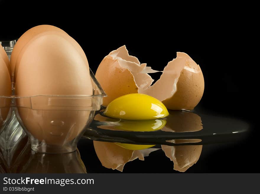 Carton of eggs with one cracked on black background. Carton of eggs with one cracked on black background