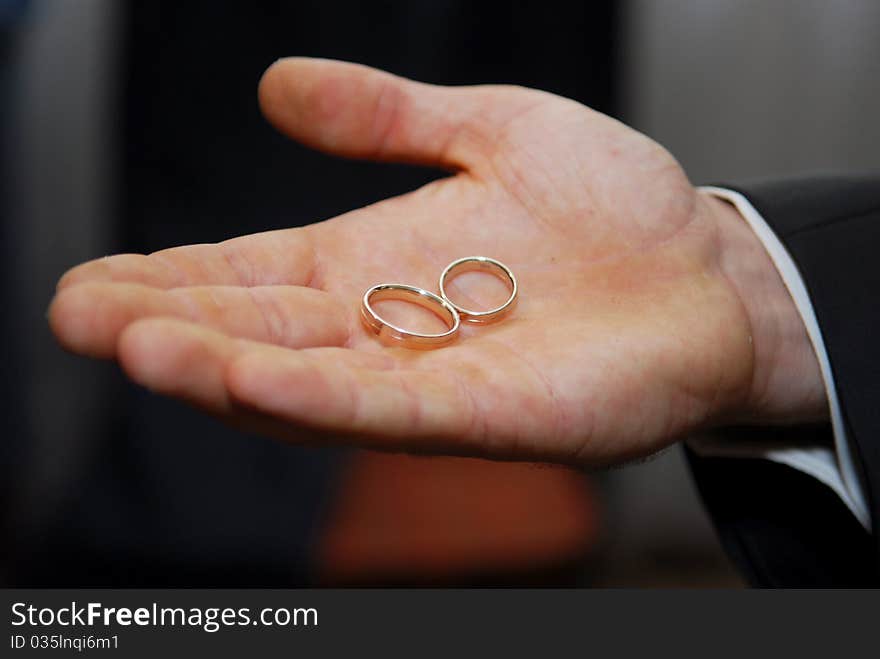 Groom holding two gold wedding rings