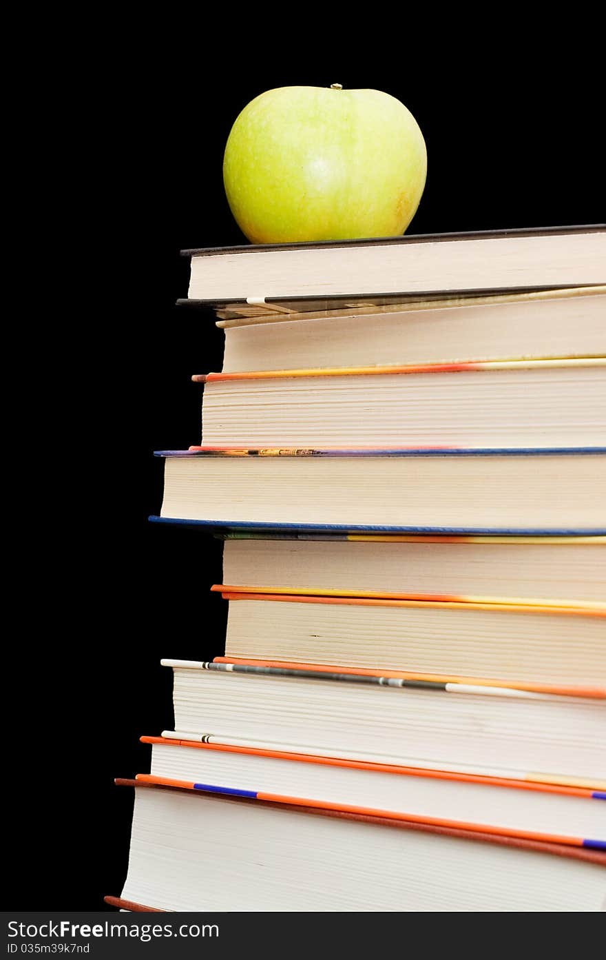 Stack of books and apple On a black background