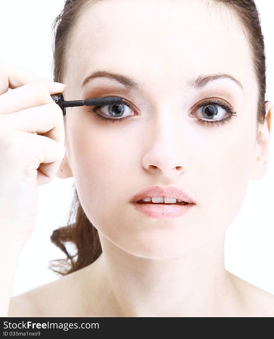 Portrait of pretty young woman applying mascara using lash brush